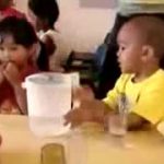 child hands pitcher of water to another child