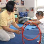 girl uses hoops while teacher helps