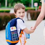child with backpack looks behind him on his way to school