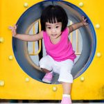 young girl climbs through toy tunnel
